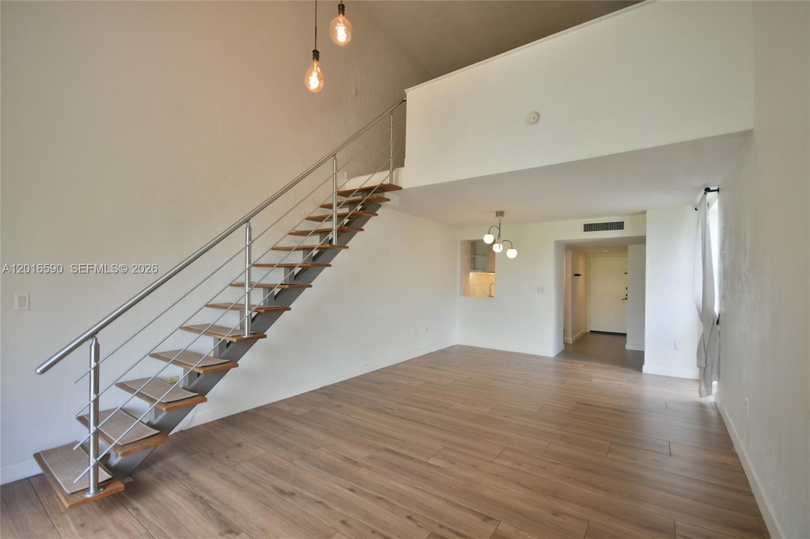 A living area features wood-look flooring, a floating staircase, and a lofted upper level — 6884 N Kendall Dr # C401, Pinecrest FL 33156, PINECREST, FL