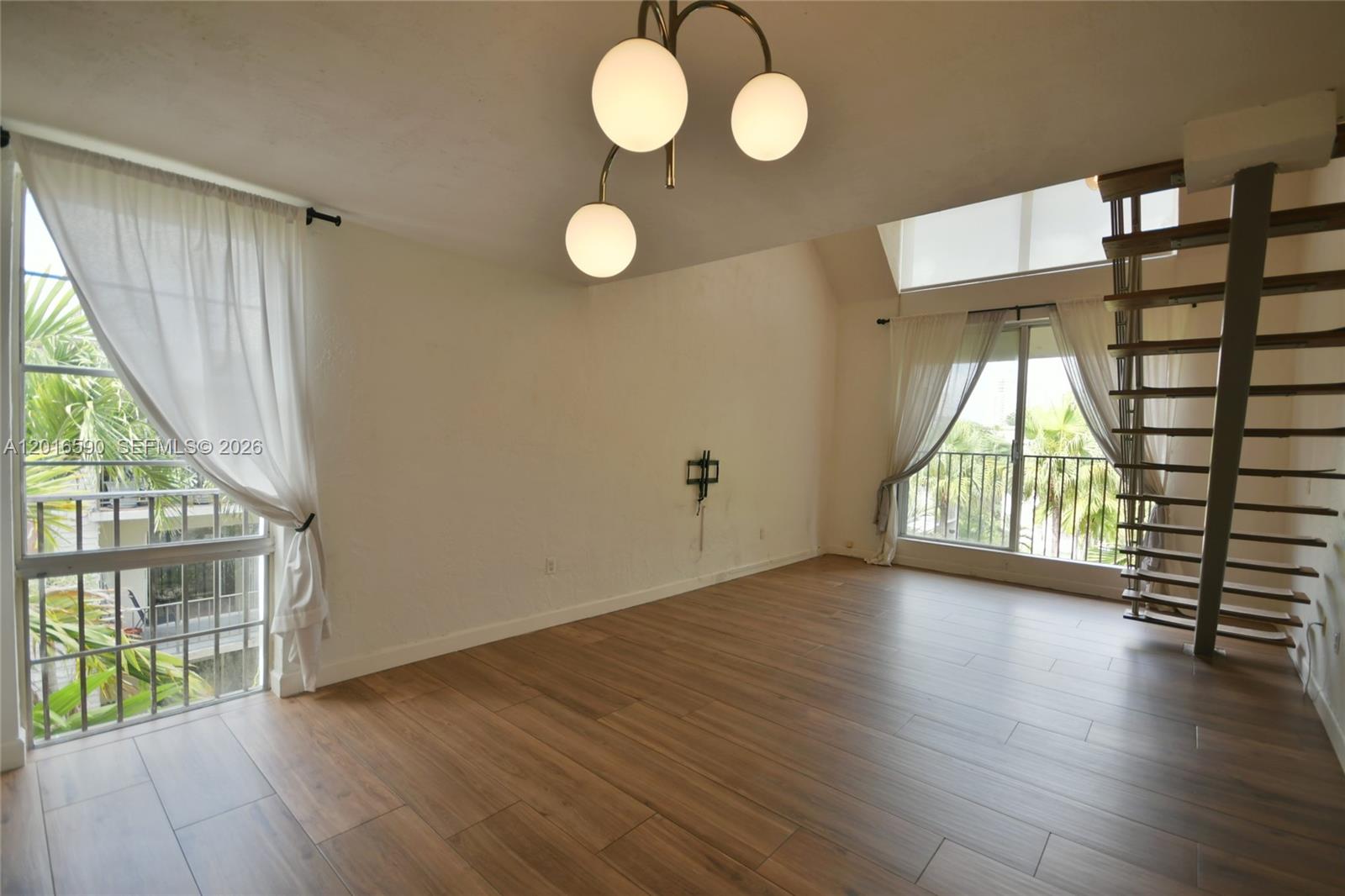A living room with wood-look tile flooring, a modern chandelier, and an open staircase — 6884 N Kendall Dr # C401, Pinecrest FL 33156, PINECREST, FL