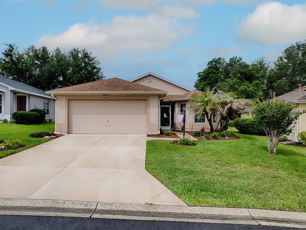 A single-story suburban house with a tan stucco exterior, a two-car garage, and a lawn — 5052 CHINA SEA, TAVARES, FL