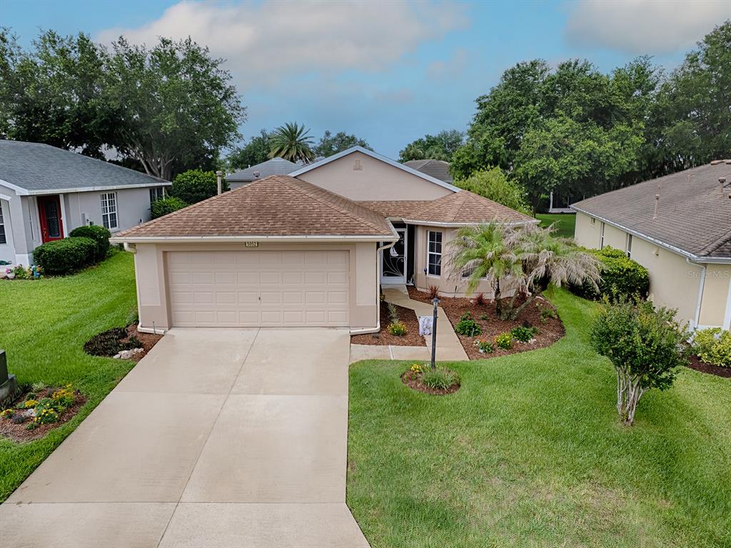 An exterior view of a single-story house with a tan stucco facade and brown roof — 5052 CHINA SEA, TAVARES, FL
