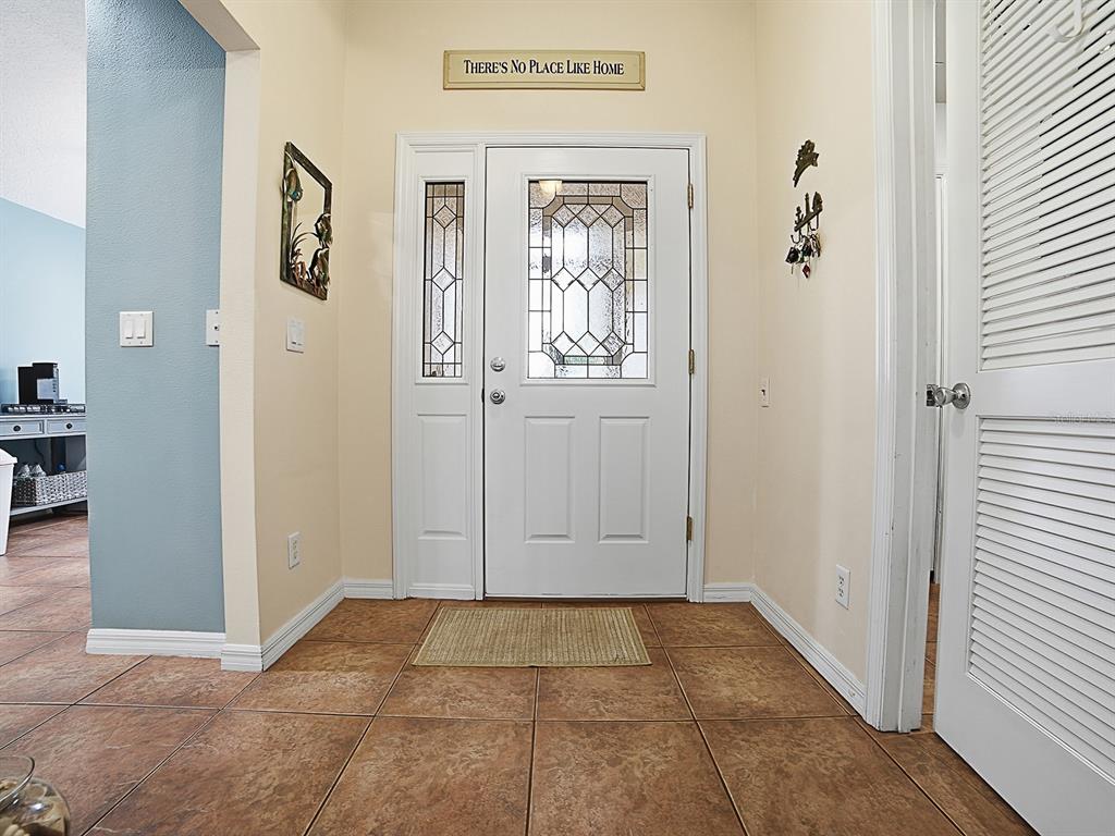 An entryway features a white front door with glass panels, tile flooring, and beige walls — 5052 CHINA SEA, TAVARES, FL