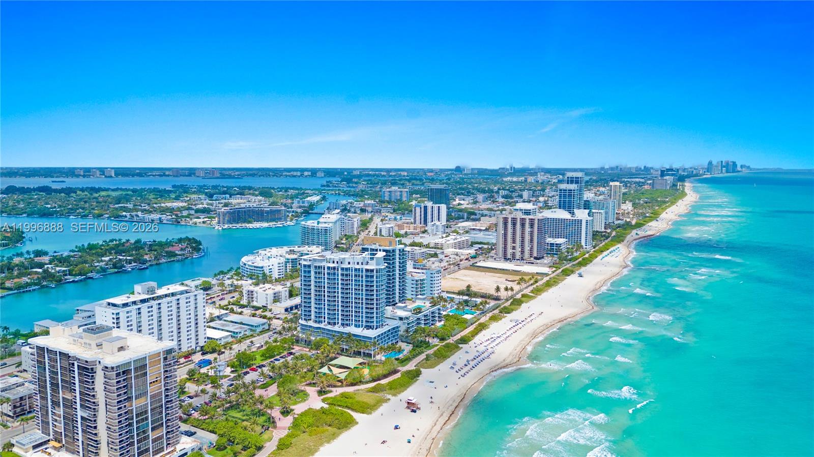 An aerial view shows high-rise buildings along a sandy beach and turquoise ocean water — 6450 Collins Ave # 204, Miami Beach FL 33141, MIAMI BEACH, FL