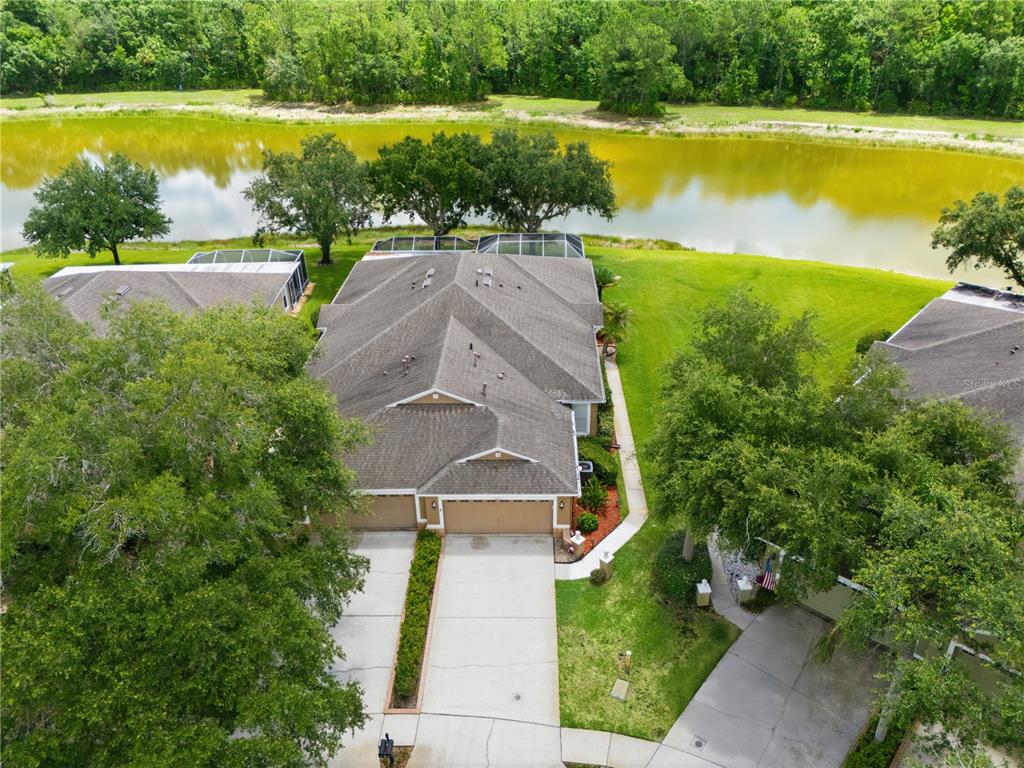 An aerial view shows a residential duplex with attached garages and screened lanais facing a pond — 19109 WHITE WING PLACE, TAMPA, FL