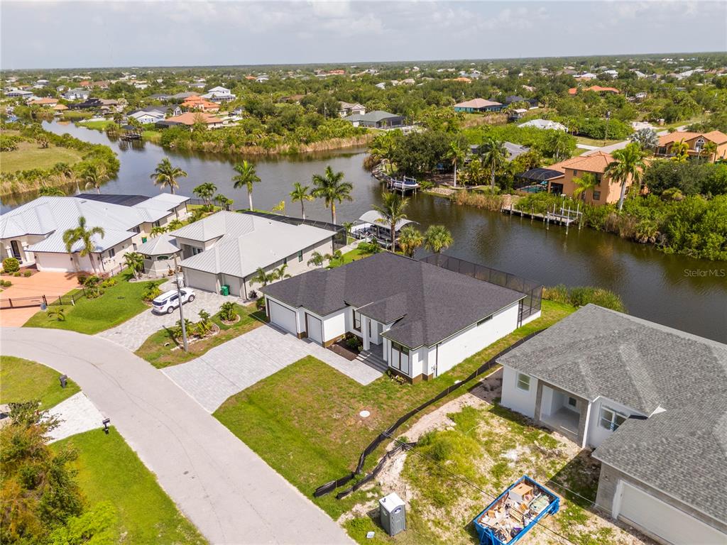 An aerial view shows several suburban houses situated along a canal with palm trees — 14958 WICHITA ROAD, PORT CHARLOTTE, FL