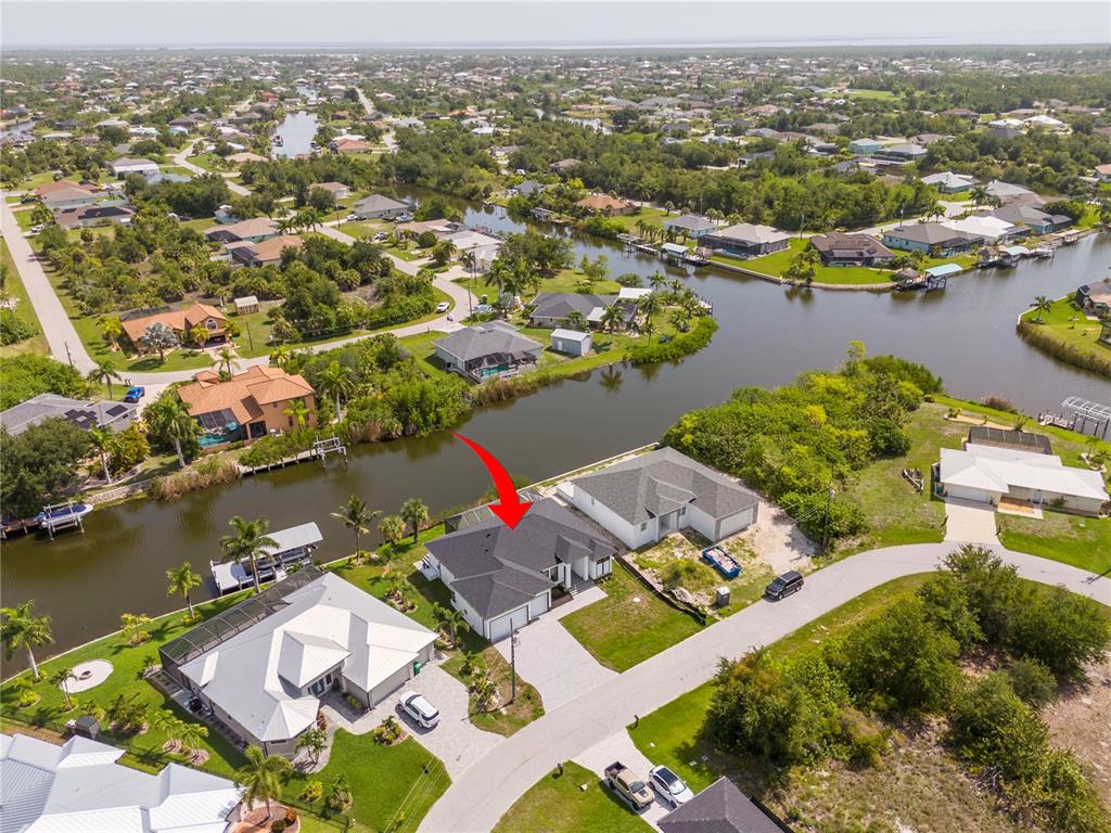 An aerial view shows a house with a dark roof situated along a canal — 14958 WICHITA ROAD, PORT CHARLOTTE, FL