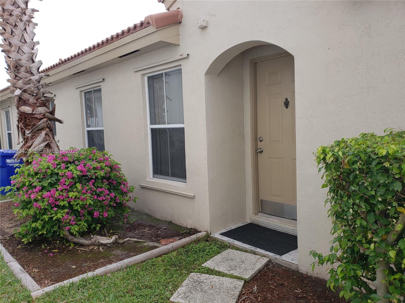 An empty room features beige tile flooring, white walls, and two windows with blinds — PEMBROKE PINES, FL