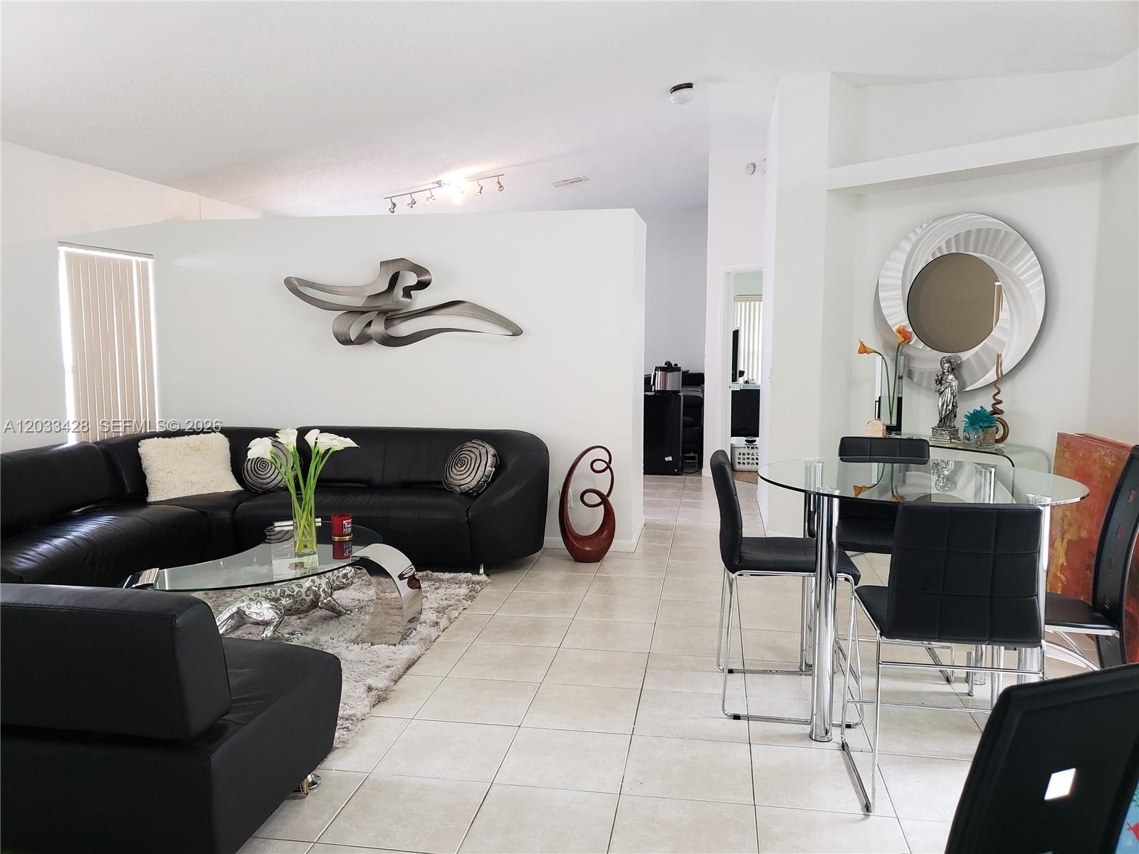 An empty room features beige tile flooring, white walls, and two windows with blinds — PEMBROKE PINES, FL