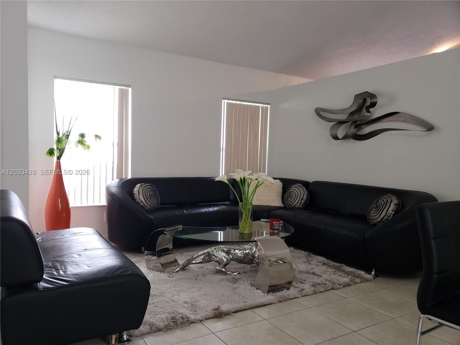 An empty room features wood-look flooring, white walls, and a single window with blinds — PEMBROKE PINES, FL