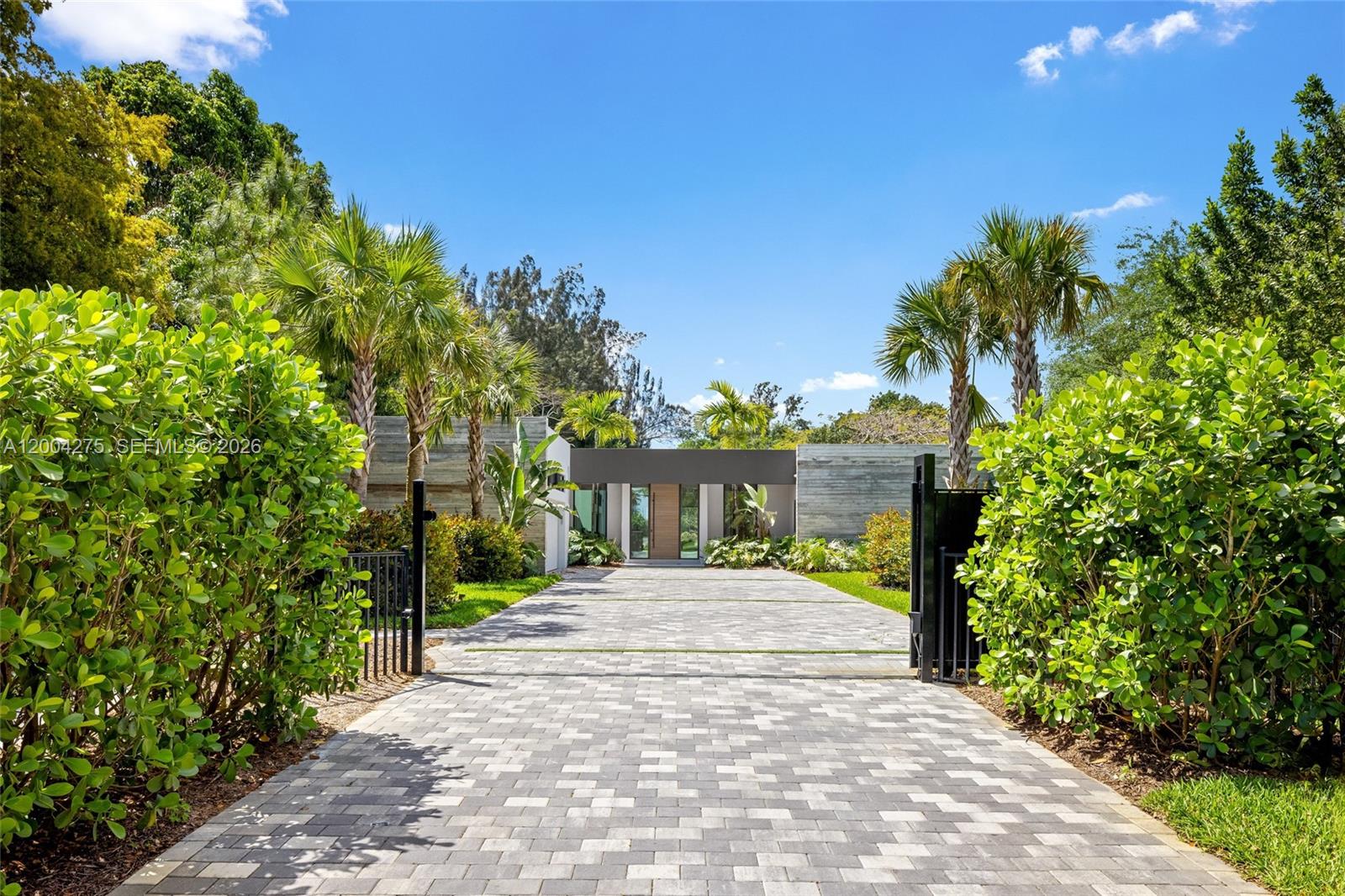 A paved driveway leads to the entrance of a modern home with concrete walls — 5700 Cypress Rd, Plantation FL 33317, PLANTATION, FL