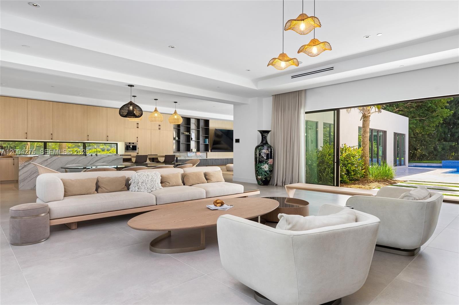 A modern open-concept living room features a large sofa, oval coffee table, and outdoor patio — 5700 Cypress Rd, Plantation FL 33317, PLANTATION, FL