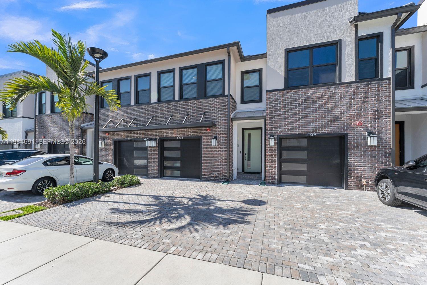 A modern two-story townhouse exterior features brick siding, black garage doors, and a paved driveway — 8351 NW 7th Ct, Plantation FL 33324, PLANTATION, FL