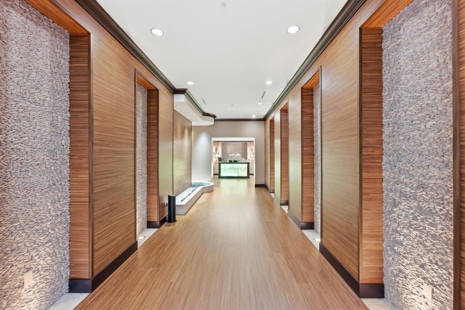 A long hallway features wood-paneled walls, stone accents, recessed lighting, and a distant reception desk — 2495 NW 66th Drive, Boca Raton FL 33496, BOCA RATON, FL
