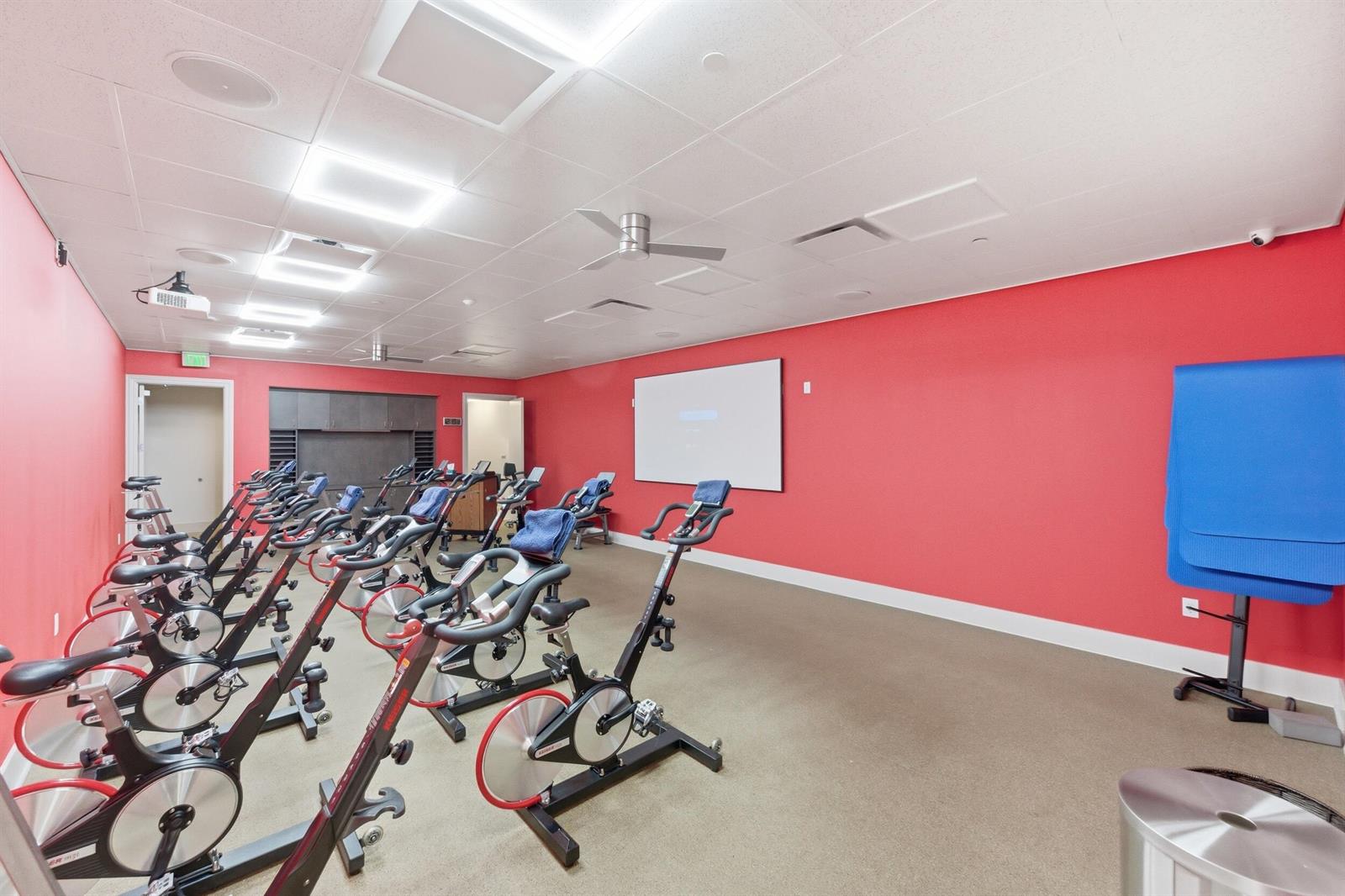 A fitness room features rows of stationary bikes, a projector screen, and bright red walls — 2495 NW 66th Drive, Boca Raton FL 33496, BOCA RATON, FL