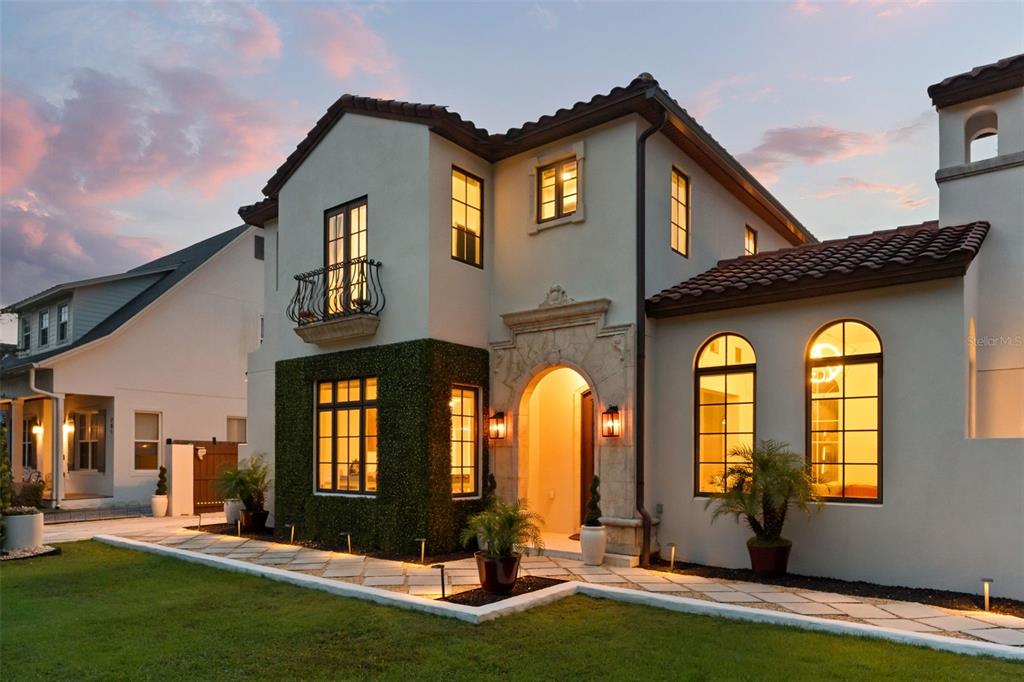 A two-story Mediterranean-style house with a stone arched entryway, balcony, and a paved walkway — 645 PANSY AVENUE, WINTER PARK, FL