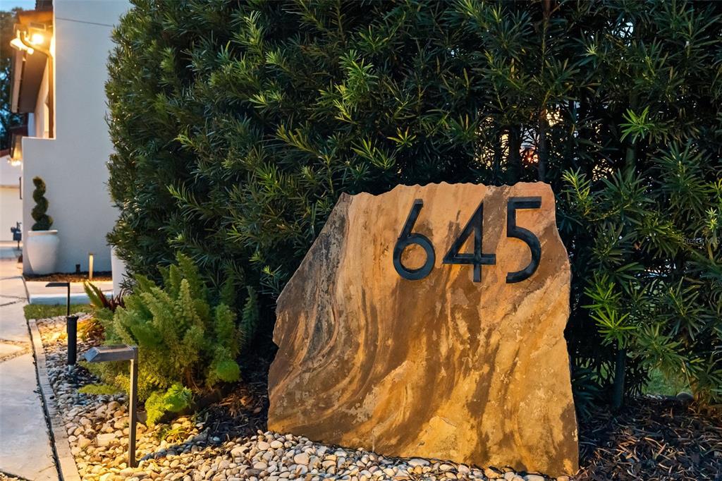 A large, natural stone slab displays the house number 645 in a landscaped front yard — 645 PANSY AVENUE, WINTER PARK, FL