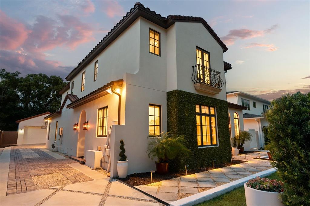 A two-story stucco home with a tiled roof, a balcony, and a paved driveway at dusk — 645 PANSY AVENUE, WINTER PARK, FL