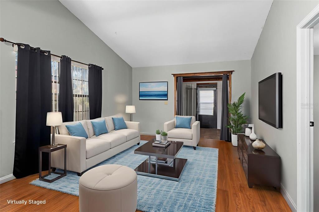 A virtually staged living room features a sofa, armchair, coffee table, and hardwood flooring — 35077 WHISPERING OAKS BOULEVARD, DADE CITY, FL