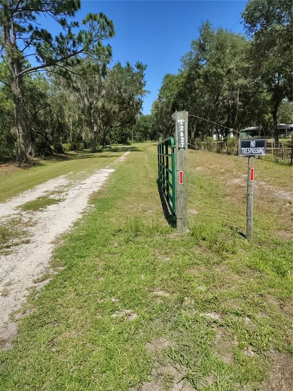 A dirt driveway leads past a green metal gate and a no trespassing sign — 12627 BLACKBERRY LANE, LAKE WALES, FL