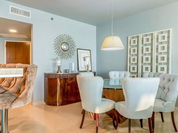 A dining room features a glass table, upholstered chairs, a sideboard, and a decorative screen — 450 Alton Rd # 1202, Miami Beach FL 33139, MIAMI BEACH, FL