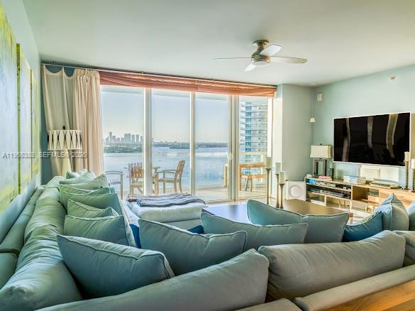 A living room features a large sectional sofa, a television, and floor-to-ceiling windows with water views — 450 Alton Rd # 1202, Miami Beach FL 33139, MIAMI BEACH, FL