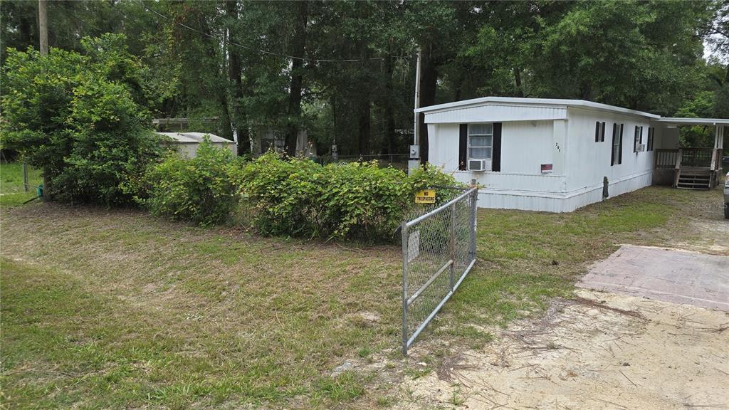A white mobile home sits on a grassy lot behind a chain-link fence — 201 NW 135TH AVENUE, OCALA, FL
