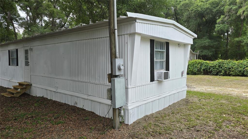 A white mobile home exterior with a utility pole and a window air conditioning unit — 201 NW 135TH AVENUE, OCALA, FL