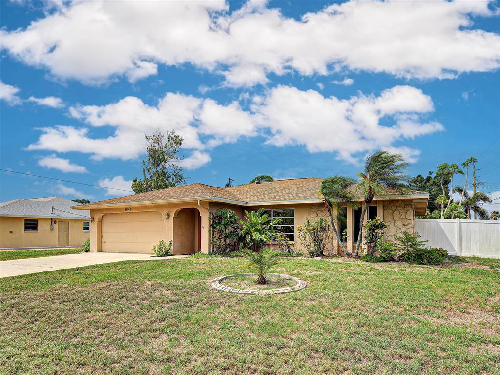 A single-story house with a tan stucco exterior, a two-car garage, and a front lawn — 3640 STERLING ROAD, VENICE, FL