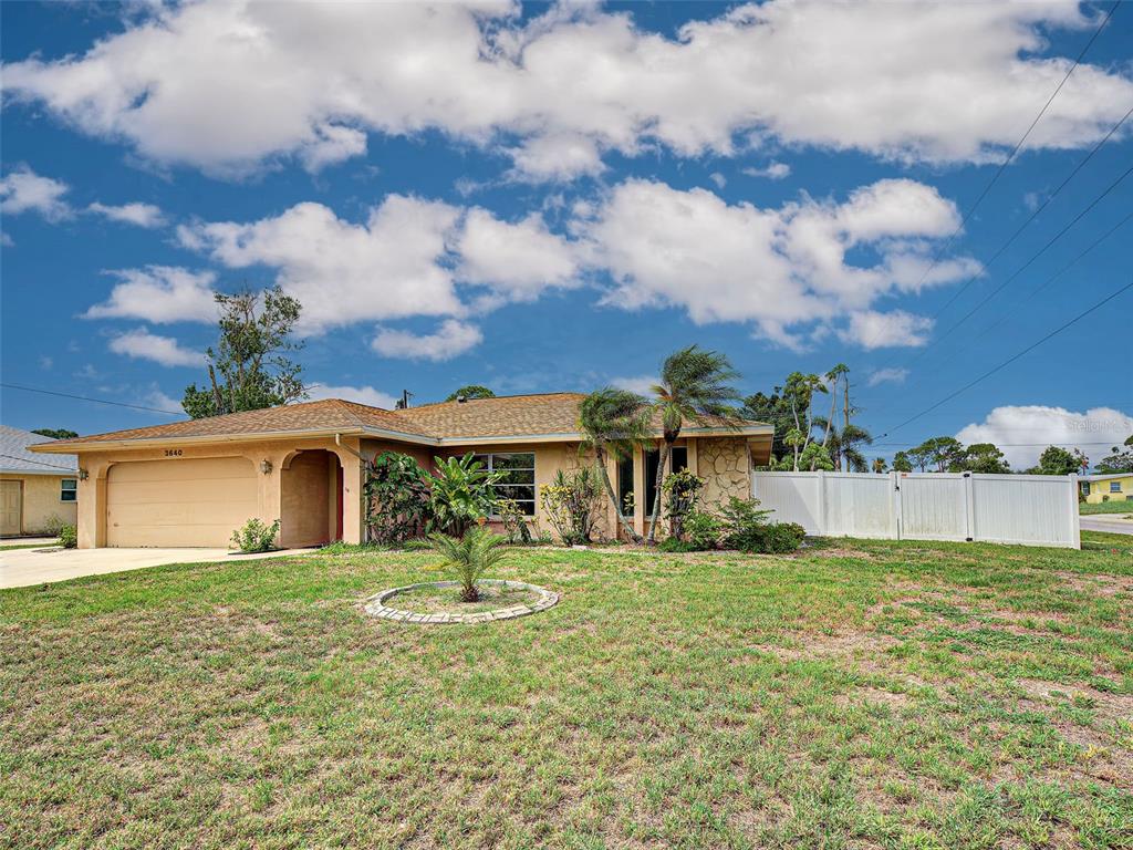 A single-story house with a tan stucco exterior, a two-car garage, and a white fence — 3640 STERLING ROAD, VENICE, FL