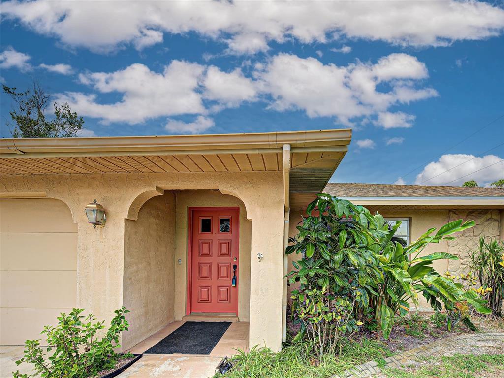 The exterior of a house features a red front door under a covered entryway — 3640 STERLING ROAD, VENICE, FL