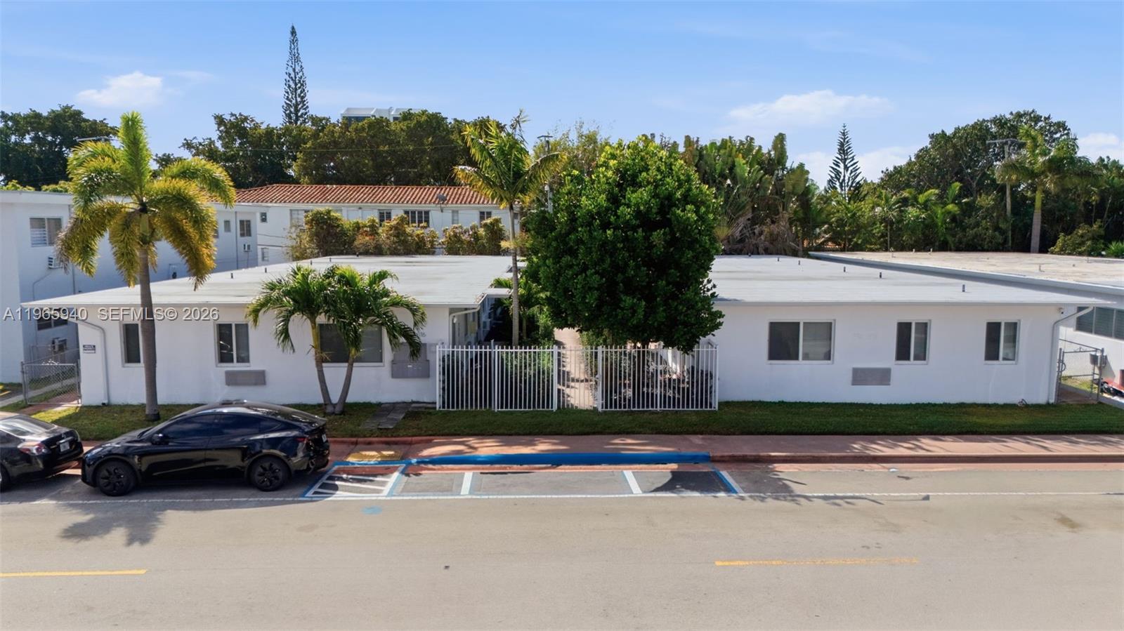 An exterior view of a single-story white apartment building with a central gated courtyard — 800 85th St, Miami Beach FL 33141, MIAMI BEACH, FL