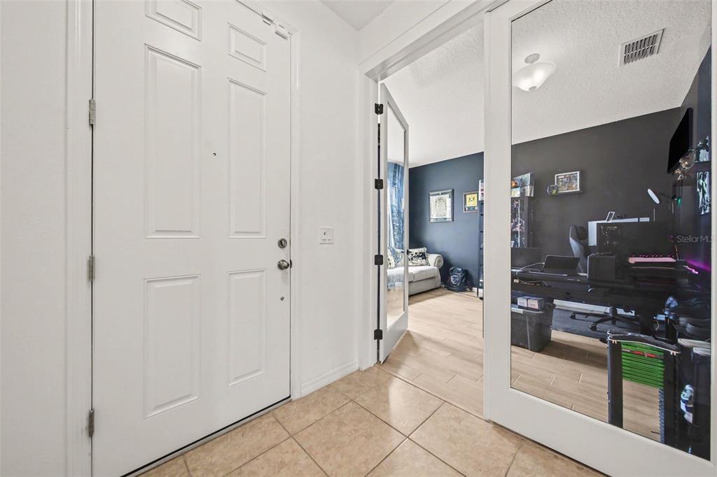 A white front door opens into a tiled entryway next to a mirrored office door — 191 HYDRA WAY, GROVELAND, FL