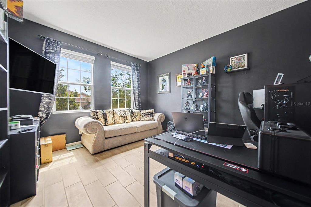 A home office with dark walls, a beige sofa, a desk, and a display cabinet — 191 HYDRA WAY, GROVELAND, FL