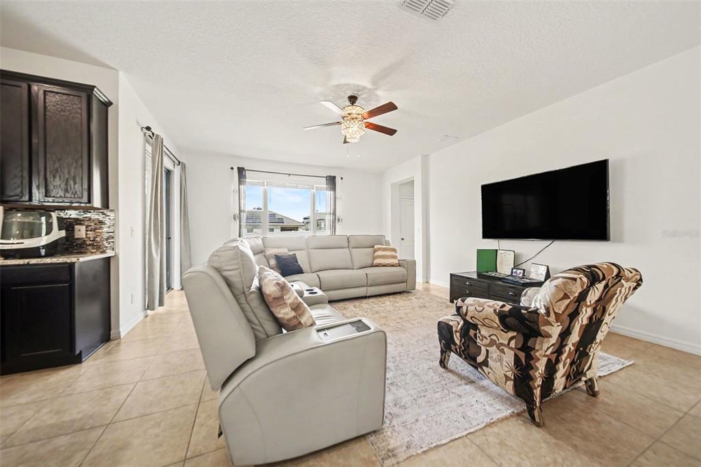 A living room features light-colored tile floors, a large sectional sofa, and a wall-mounted television — 191 HYDRA WAY, GROVELAND, FL