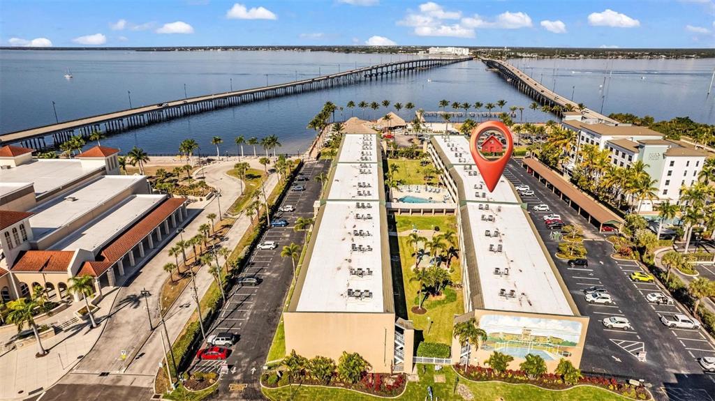 An aerial view shows two long apartment buildings with parking lots and a nearby bridge — 150 HARBORSIDE AVENUE UNIT 209, PUNTA GORDA, FL