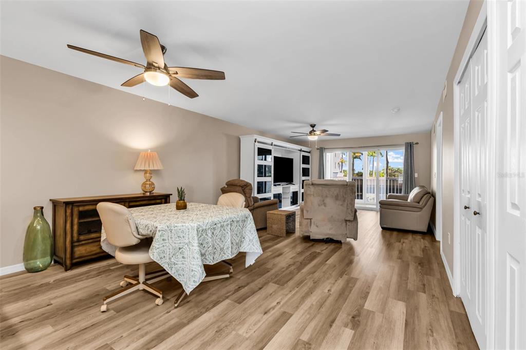 A living and dining area features wood-look flooring, a ceiling fan, and a sliding glass door — 150 HARBORSIDE AVENUE UNIT 209, PUNTA GORDA, FL