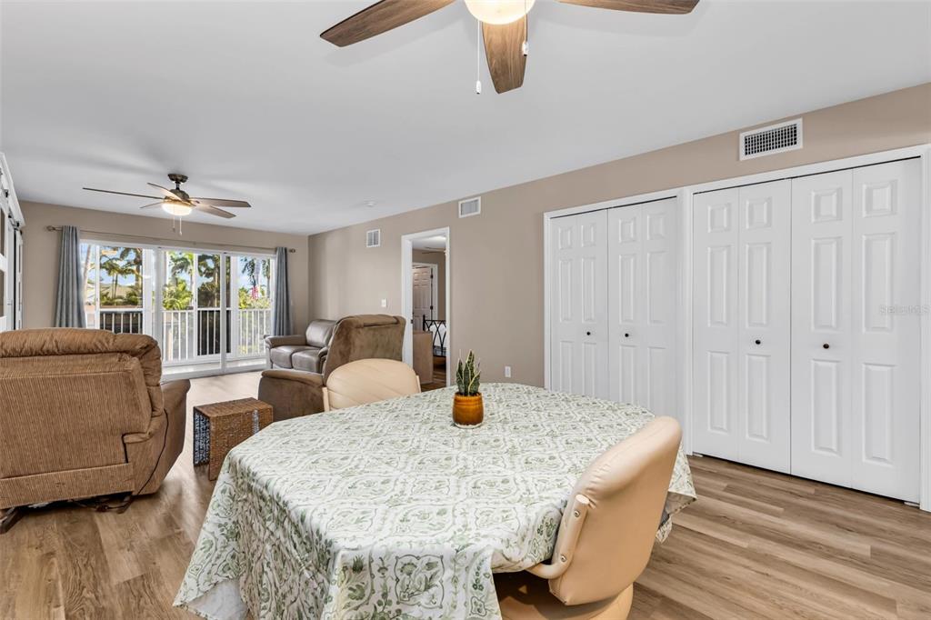 A living and dining area features wood-look flooring, ceiling fans, and sliding glass balcony doors — 150 HARBORSIDE AVENUE UNIT 209, PUNTA GORDA, FL