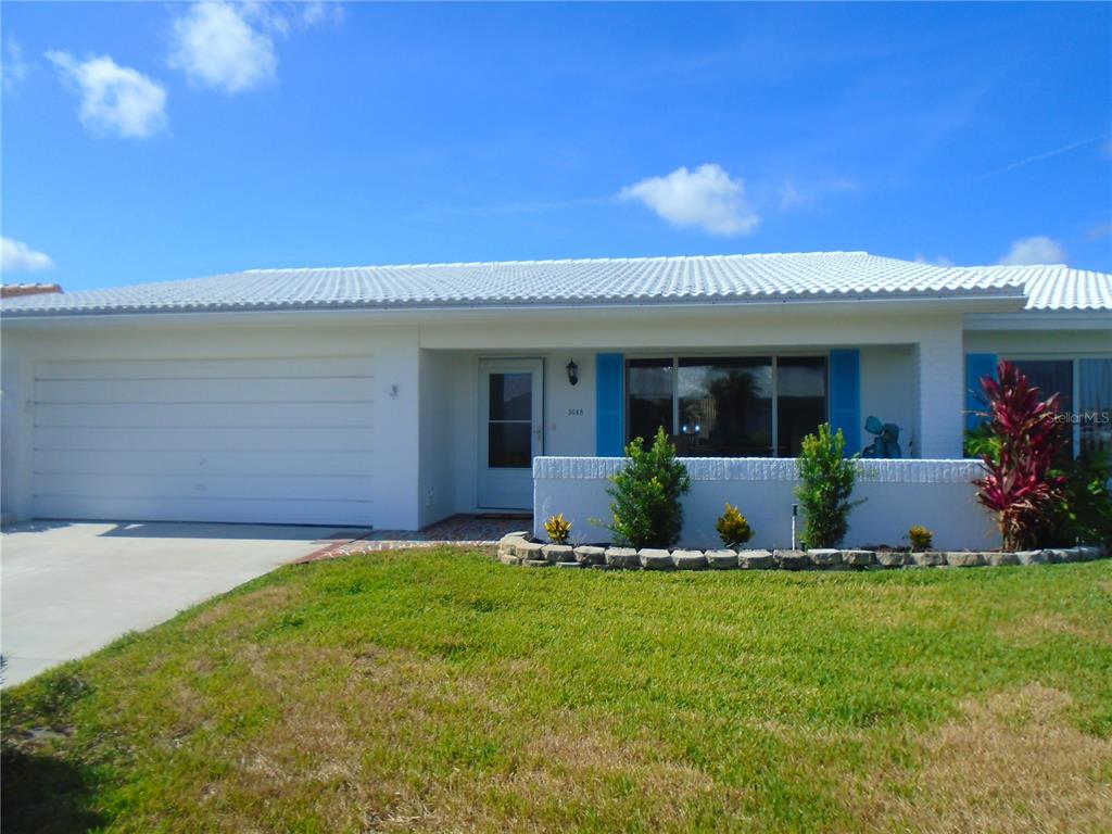 A single-story house with a white exterior, a two-car garage, and a front garden bed — 3648 91ST AVENUE N UNIT 6, PINELLAS PARK, FL