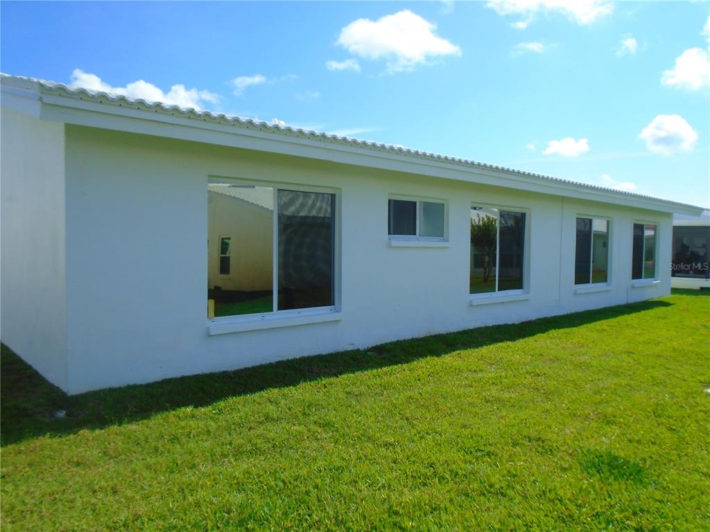 The exterior of a white house features a long wall with several windows and grass — 3648 91ST AVENUE N UNIT 6, PINELLAS PARK, FL