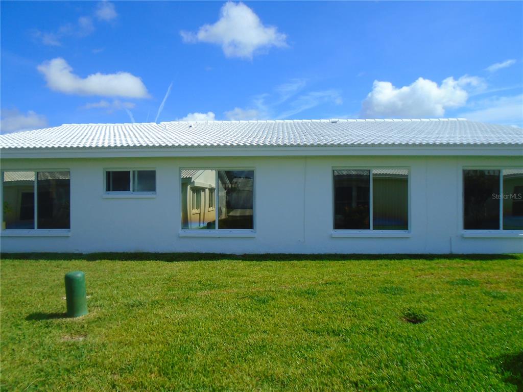 The exterior of a white, single-story house features a tiled roof and several windows — 3648 91ST AVENUE N UNIT 6, PINELLAS PARK, FL