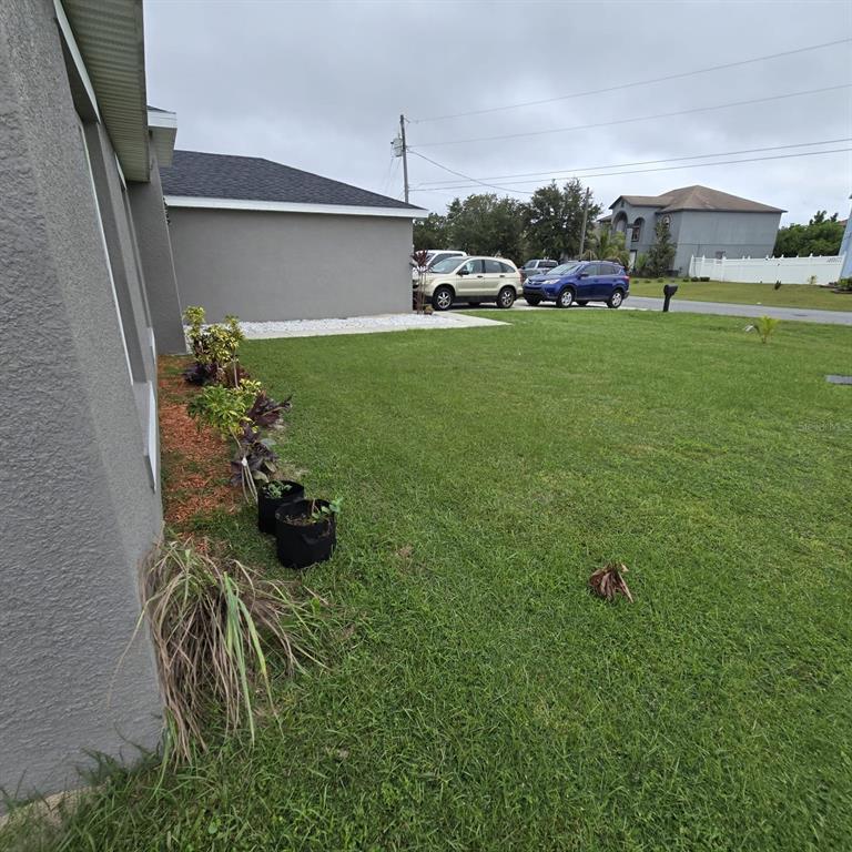 A side view of a house exterior featuring a lawn, landscaping, and parked cars — 540 BRISTOL CIRCLE, KISSIMMEE, FL
