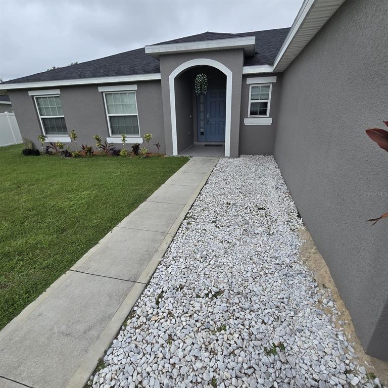 The exterior of a gray house features a concrete walkway and a white rock bed — 540 BRISTOL CIRCLE, KISSIMMEE, FL