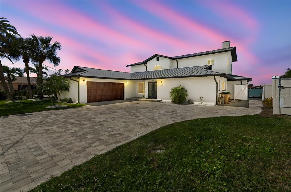 A two-story white house with a metal roof and a paved driveway at sunset — 478 HARBOR DRIVE N, INDIAN ROCKS BEACH, FL