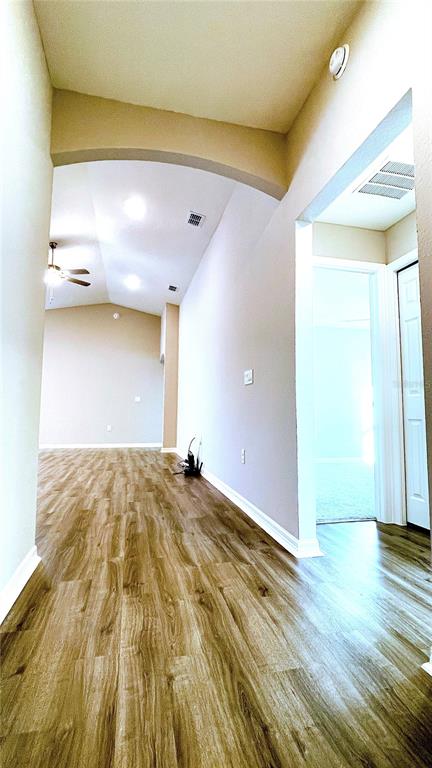 A hallway with wood-look flooring leads to an open living area with a ceiling fan — 1387 MOUNTAIN FLOWER LANE, DAVENPORT, FL