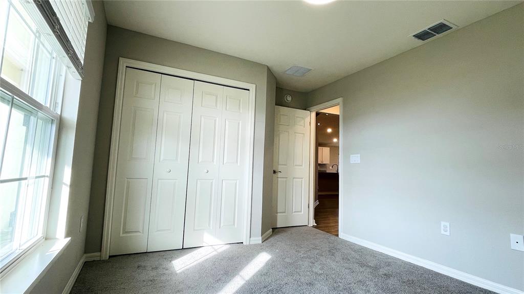 A bedroom features gray carpet, light-colored walls, a white bi-fold closet, and an open doorway — 1387 MOUNTAIN FLOWER LANE, DAVENPORT, FL