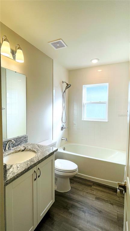 A bathroom features a granite-topped vanity, a toilet, and a shower-tub combination with white tile — 1387 MOUNTAIN FLOWER LANE, DAVENPORT, FL