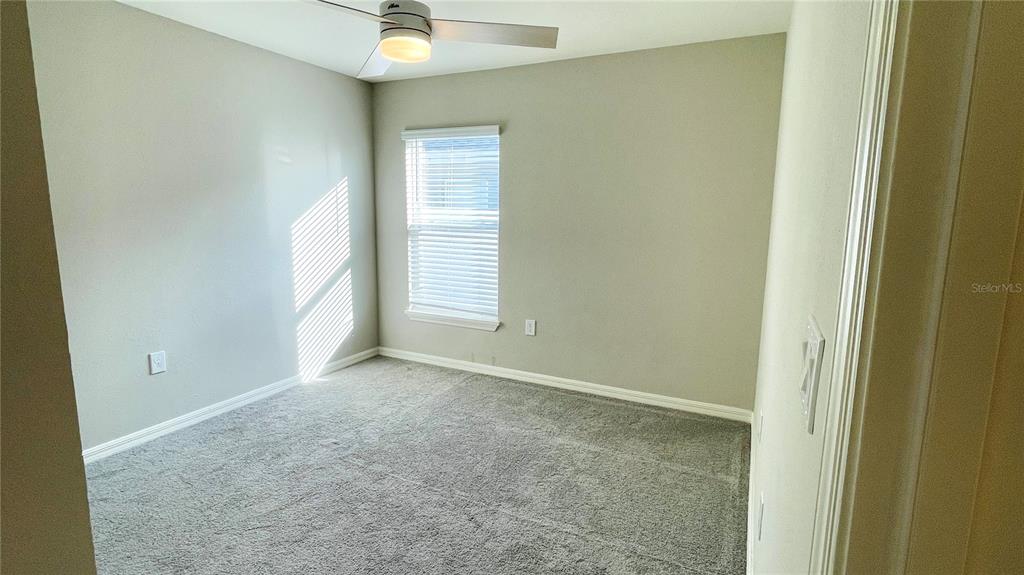 A bedroom with gray carpet, light-colored walls, a ceiling fan, and a single window — 1387 MOUNTAIN FLOWER LANE, DAVENPORT, FL
