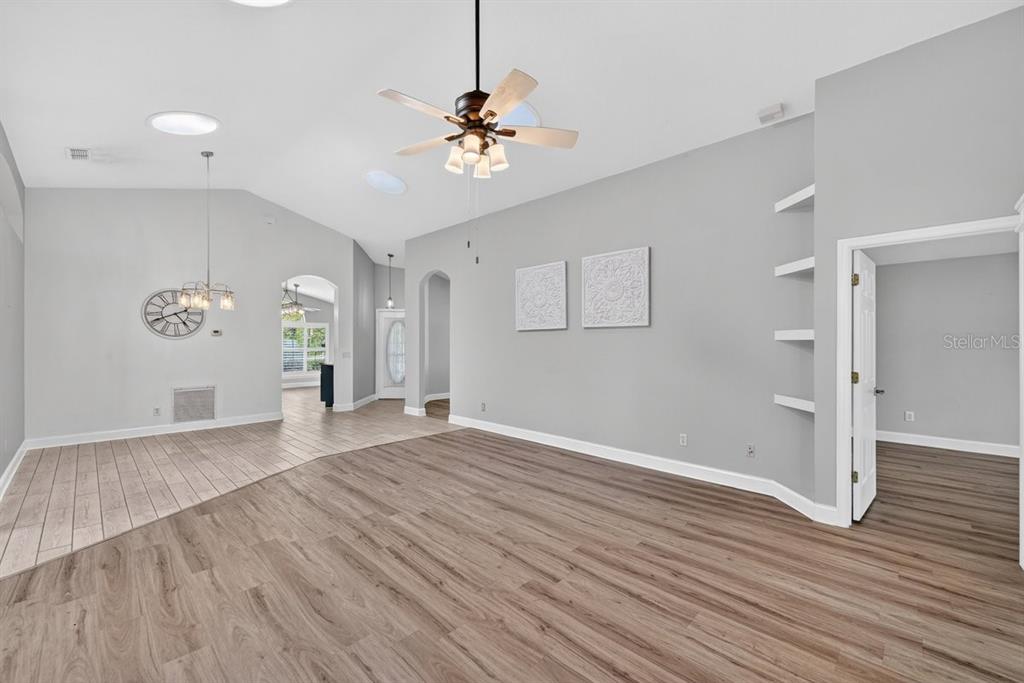 A spacious living area with light gray walls, wood-look flooring, and a vaulted ceiling — 614 JOHN THOMAS AVENUE, DELAND, FL