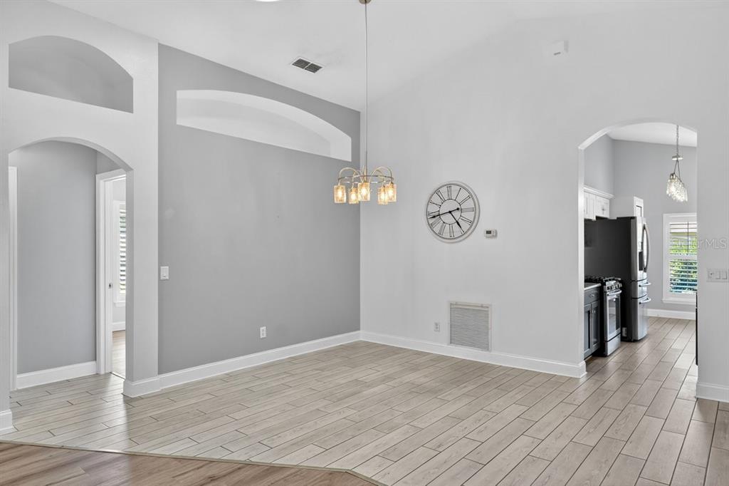 A dining area with light wood-look tile flooring, gray accent walls, and a hanging chandelier — 614 JOHN THOMAS AVENUE, DELAND, FL