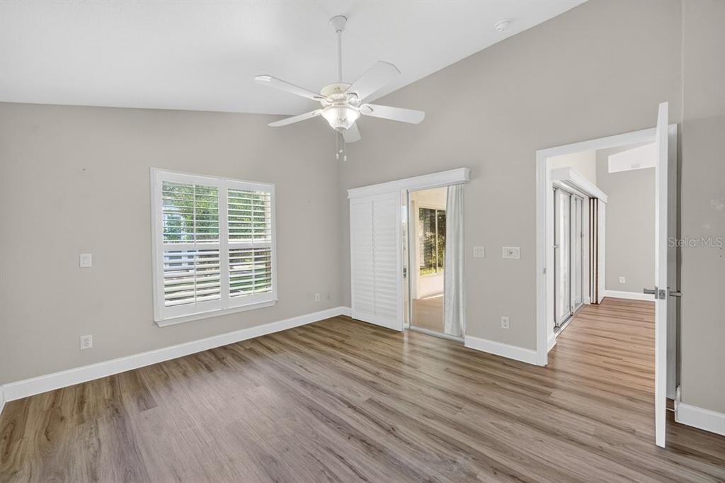 A room with light gray walls, wood-look flooring, a ceiling fan, and sliding glass doors — 614 JOHN THOMAS AVENUE, DELAND, FL