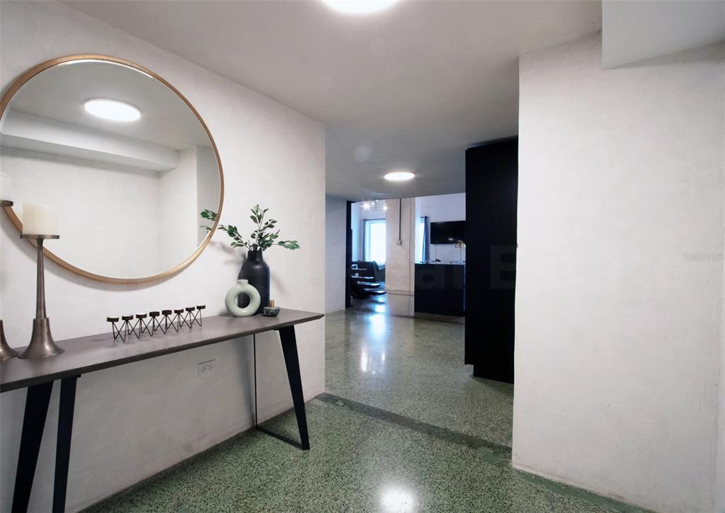 A modern entryway features a console table, a round mirror, and polished terrazzo flooring — 203 RECINTO SUR STREET UNIT 2, OLD SAN JUAN, PR